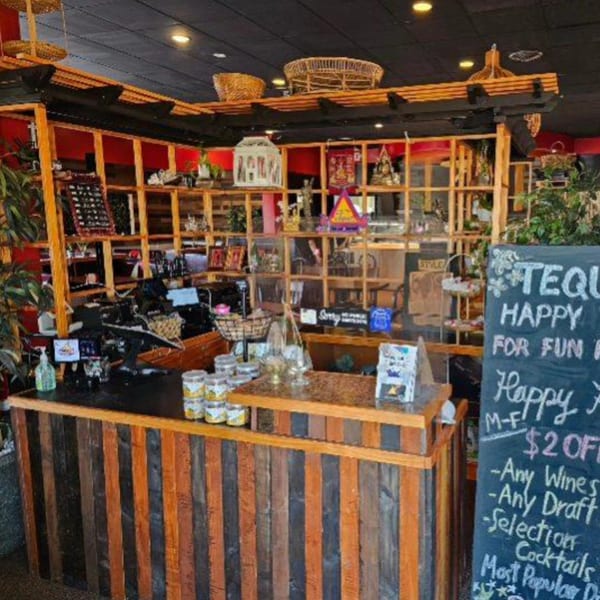 The Elephant Thai restaurant's rustic wooden reception counter with shelves displaying decor and a chalkboard sign.