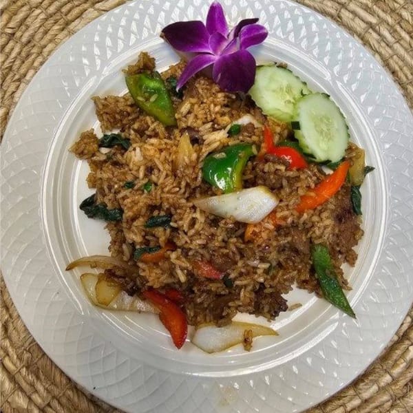 Elephant Thai's basil fried rice with vegetables, garnished with a purple orchid and cucumber slices.