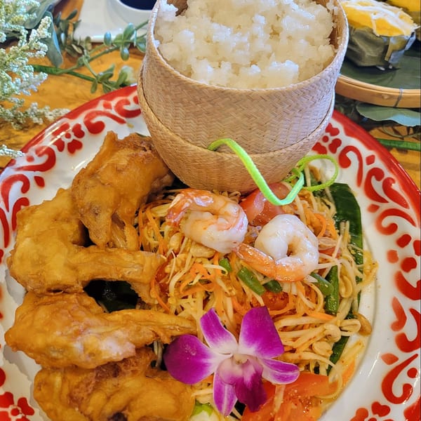 Elephant Thai's Som Tum with fried chicken, shrimp, sticky rice, and a purple orchid garnish.