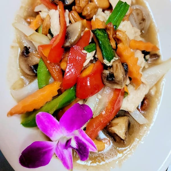 Elephant Thai's cashew nut stir-fry with chicken, vegetables, and a purple orchid garnish.